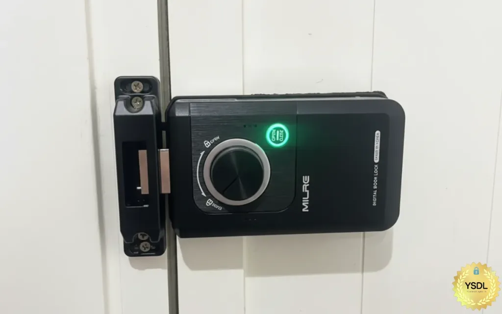 安裝於白色門上的 MILRE 黑色數位電子鎖（Digital Door Lock）主機特寫，中央旋鈕亮起綠燈，右下角附有 YSDL 品牌標籤