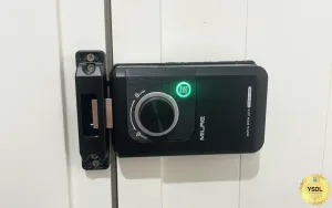 安裝於白色門上的 MILRE 黑色數位電子鎖（Digital Door Lock）主機特寫，中央旋鈕亮起綠燈，右下角附有 YSDL 品牌標籤